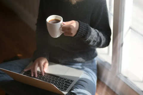 Girl working on laptop and drinking coffee