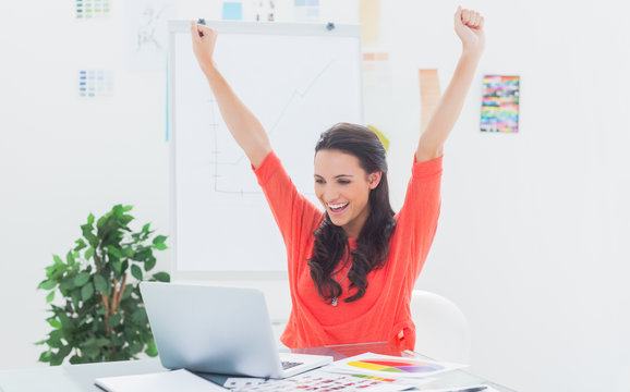 Excited woman raising her arms while working