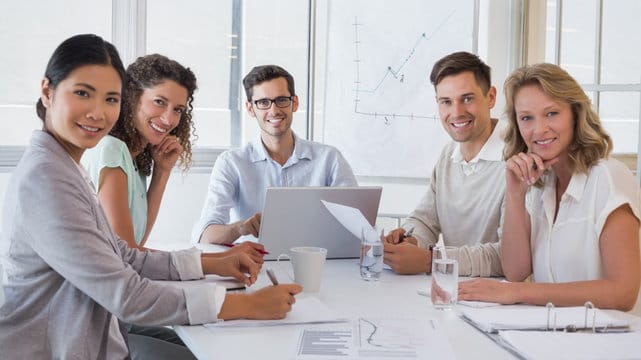 Casual business team having a meeting smiling at camera