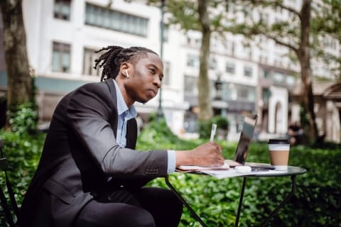 Man taking notes at desk outside