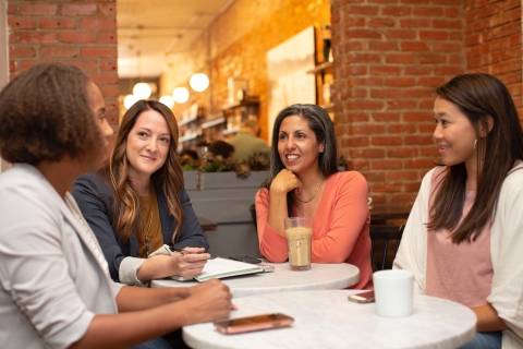 four women sitting around a table talking
