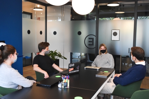 Coworkers sitting around a conference table with masks
