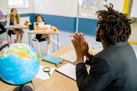 Teacher sitting at desk looking at students