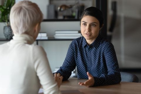 Person sitting and talking to a colleagues at a table