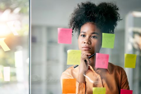 Employee looking at post it notes on an office wall